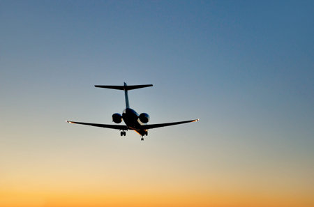 Aircraft landing on blue and orange sky at sunset