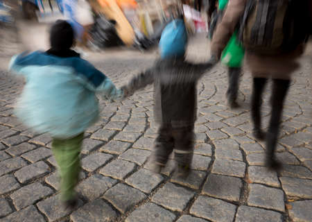 Legs of kids in blurred motion walking on street with cobble stonesの写真素材
