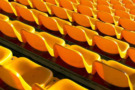Rows of empty yellow plastic seats at sports stadiumの写真素材