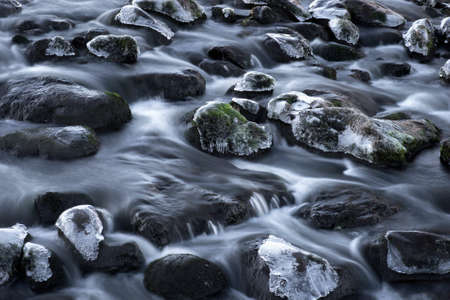 Rocks in streaming water with caps of ice, long exposureの写真素材