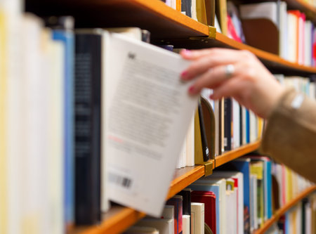 Hand of woman selecting a book from book shelf, blurred mtion