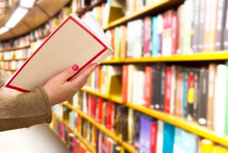 Woman with book in hand in library