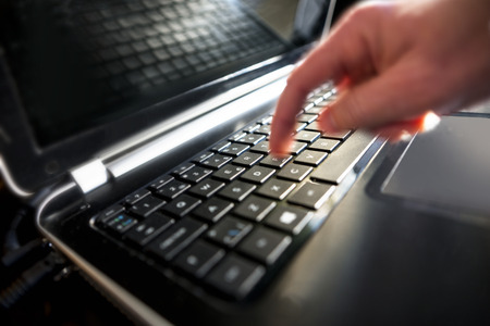 Finger in blurred motion pressing key on laptop keyboardの写真素材