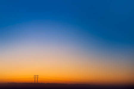 Electric power line with pylons on colorful evening skyの写真素材