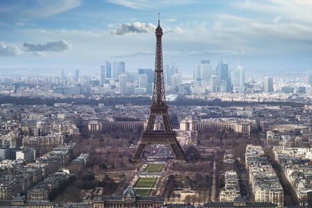 aerial view of eiffel tower on bright day with blue sky and fluffy clouds. La Defence brightly lit in background.の写真素材