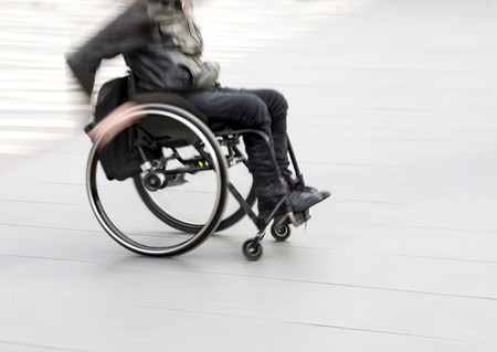 Young man in wheelchair in blurred motionの写真素材