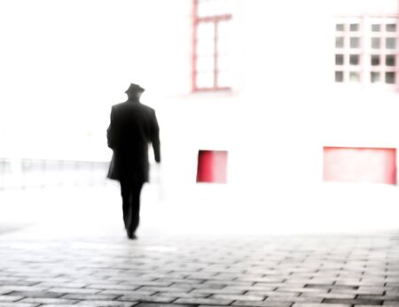 Rear view of silhouette of man in hat in blurred motion in cityの写真素材