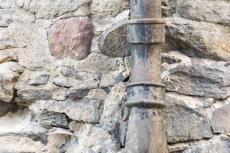 Old rusty black metal drainpipe on urban stone buildingの写真素材