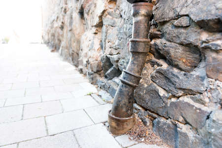 Old rusty black metal drainpipe on urban stone buildingの写真素材