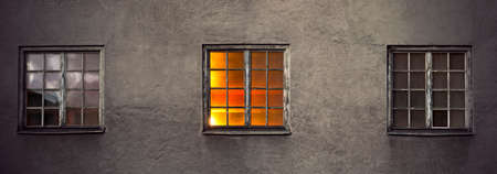 old concrete wall of industrial building with three windows at nightの写真素材