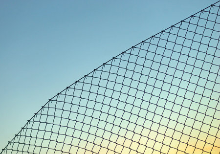 Background with chain link fence on blue skyの写真素材