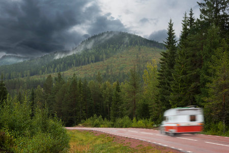 Car with trailer in gloomy scandinavian rural mountain landscapeの写真素材