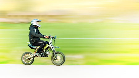 Young man on small motorbike or moped in blurred motionの写真素材