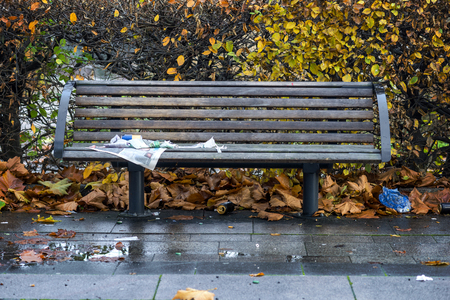 wooden park bench with wet newspaper on rainy autumn dayの写真素材