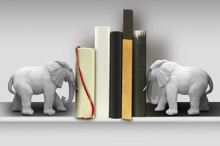 Books on shelf held in place by two heavy marble elefantsの写真素材