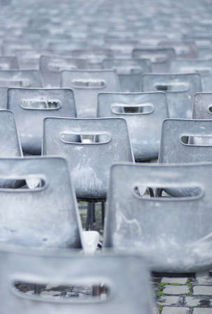 Empty plastic chairs outdoors on rainy day, one chair in red colorの写真素材