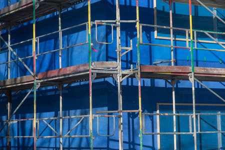 Scaffolding in bright sunshine, with blue canvas in background