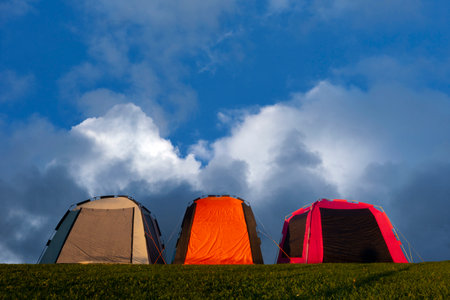 Three tents on blue sky with fluffy cloudsの写真素材
