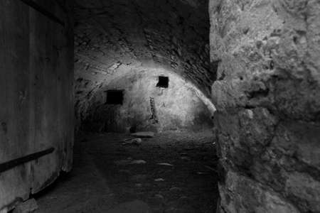 Old dark prison cell in black and white, with scullの写真素材