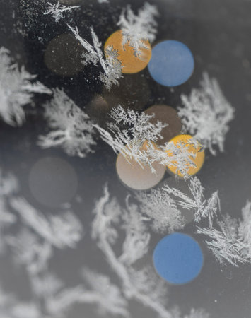 Ice crystals on glass, with blurred lights in backlground