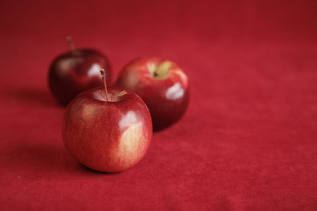 Three red apples on a red background