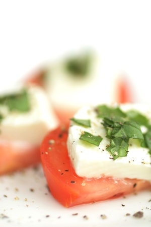 Close up of a tomatoes and boccocini cheese with fresh basil on topの写真素材