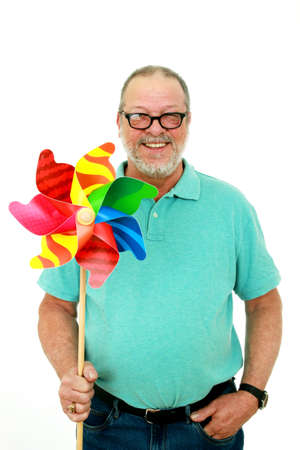Smiling senior man holding a pinwheel on a white backgroundの写真素材