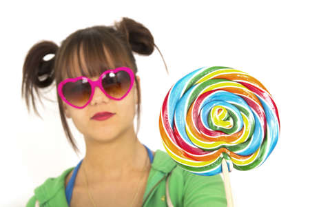 serious teenager with heart shape glasses holding a multicolored candyの写真素材