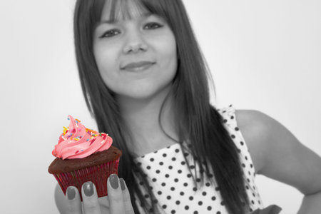 Young teenager holding a pink cupcake in handの写真素材