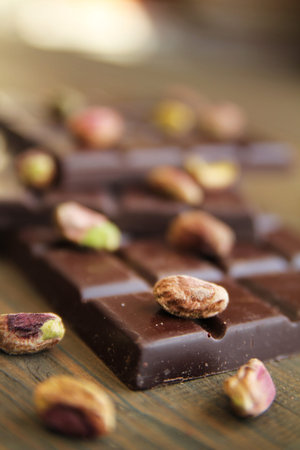 Dark chocolate and pistachios on a wooden cutboardの写真素材