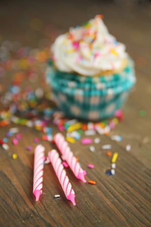 Three candles with a vanilla cupcake in backgroundの写真素材