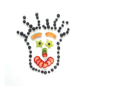 Smiling face made with fresh fruits on white backgroundの写真素材