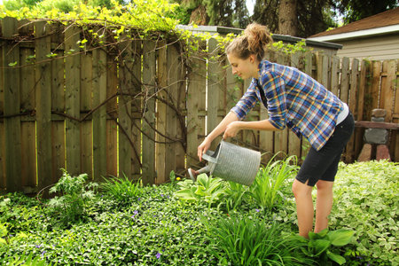 Teenager watering flowers in their garden