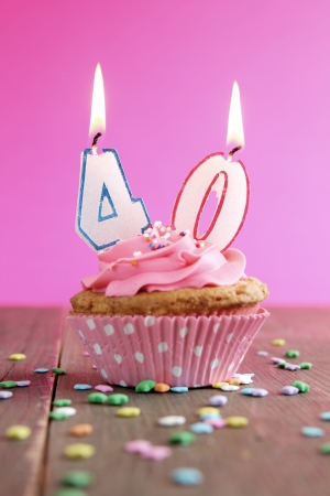 Number forty birthday candles on a pink cupcake on a wooden tableの写真素材