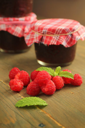 Raspberry jam, fresh fruits and mint on a wooden table