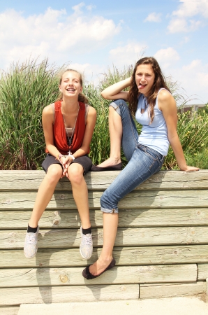 Two teenagers having fun on a wood wallの写真素材
