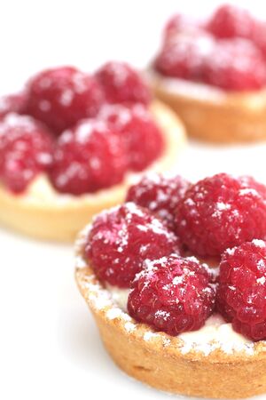 three raspberry tarts on white with sugar powder on topの写真素材