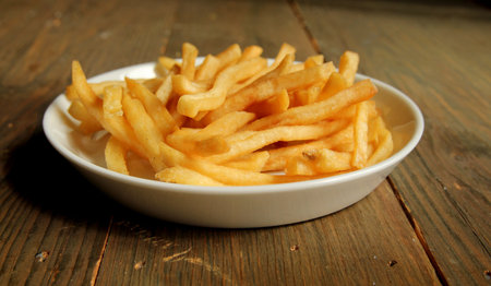 French fries with salt in a plate on a wooden table