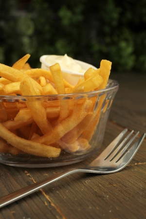 French fries with salt and mayonnaise in a clear bowl with fork の写真素材