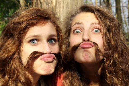 Two best friends doing mustaches with their hairsの写真素材