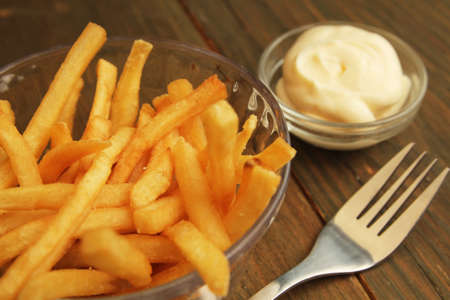 French fries with salt and mayonnaise in a clear bowl with fork の写真素材
