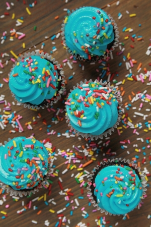 Top view of blue icing cupcakes surround by colored candiesの写真素材