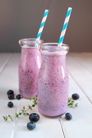 Two blueberry smoothie present in a litlle milk bottle with blue strawの写真素材