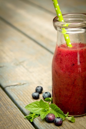 Half of blueberry smoothie with fresh fruits on a rustic woodの写真素材