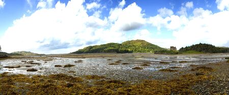 View of  Eilean Tioram in Loch Moidart at low tide with a cloudy and blue  sky in Highland, Scotlandの写真素材