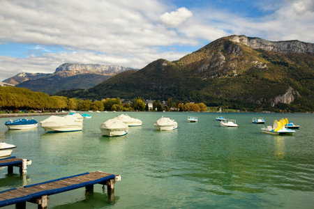 Boats at the riverside in Annecy, France and the Alpes in backgroundの写真素材