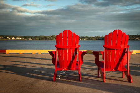 2 red Adirondack chairs in front of the ocean in Prince Edward island の写真素材