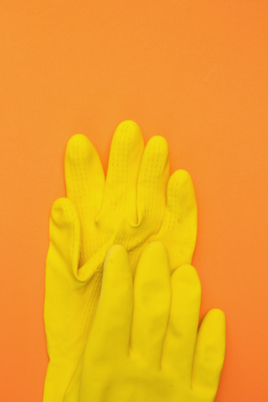 Yellow rubber gloves on an orange backgroundの写真素材