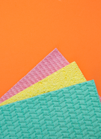 Top view of three different colours of cleaning sponges on an orange backgroundの写真素材