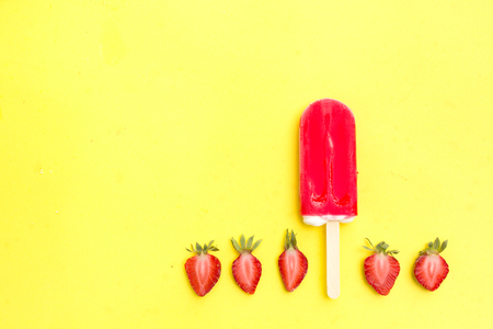 Strawberry popsicle with fresh strawberry on a yellow backgroundの写真素材